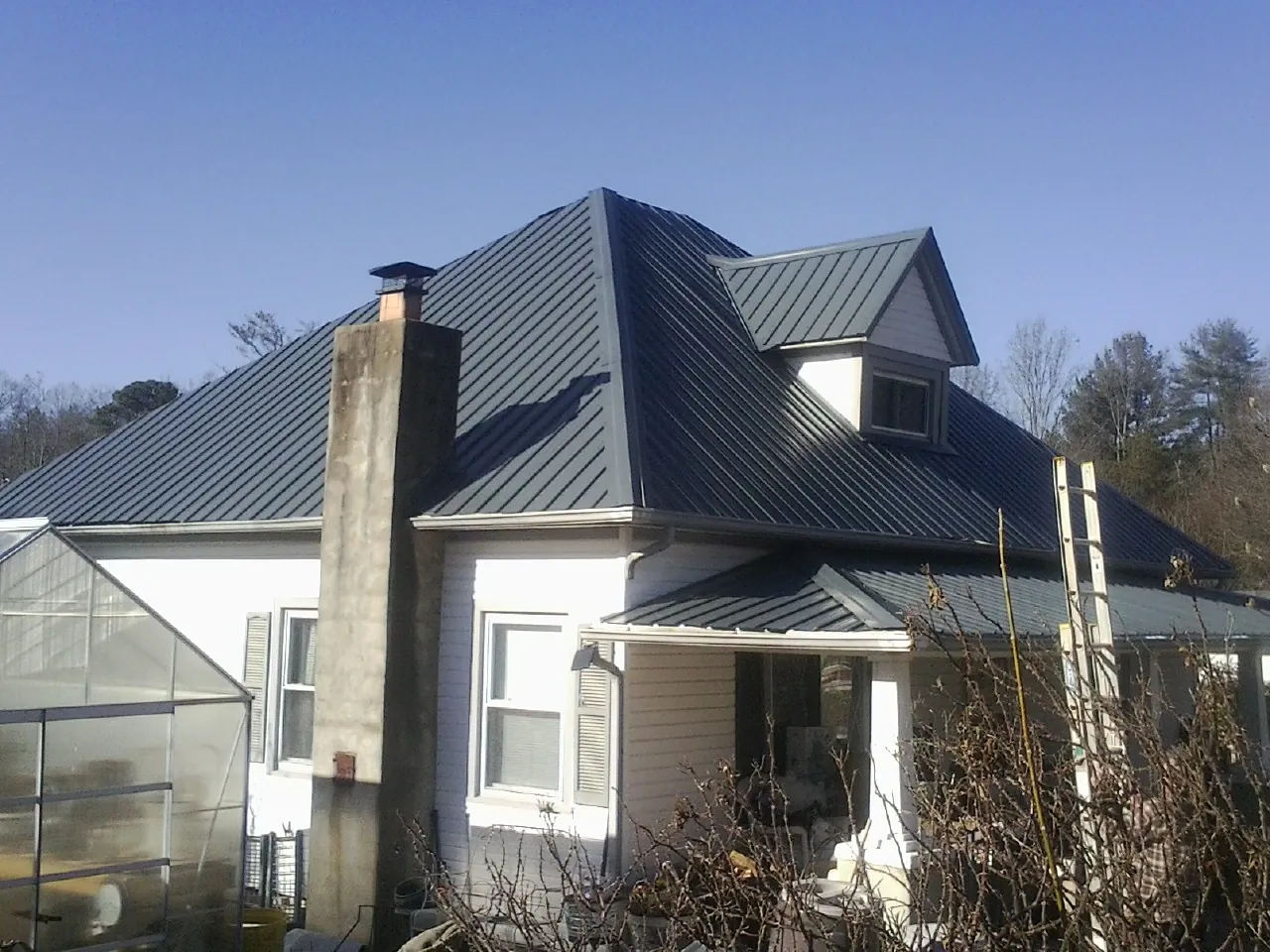 Dark blue standing seam metal roof on a white farmhouse with dormer — Slate & Tile Roof Repair by Roofing Brothers in Sherman Oaks