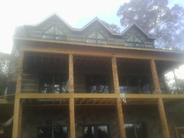 Dormers and porch framing on a large log home under construction — Roof Coating work by our crew in Sherman Oaks