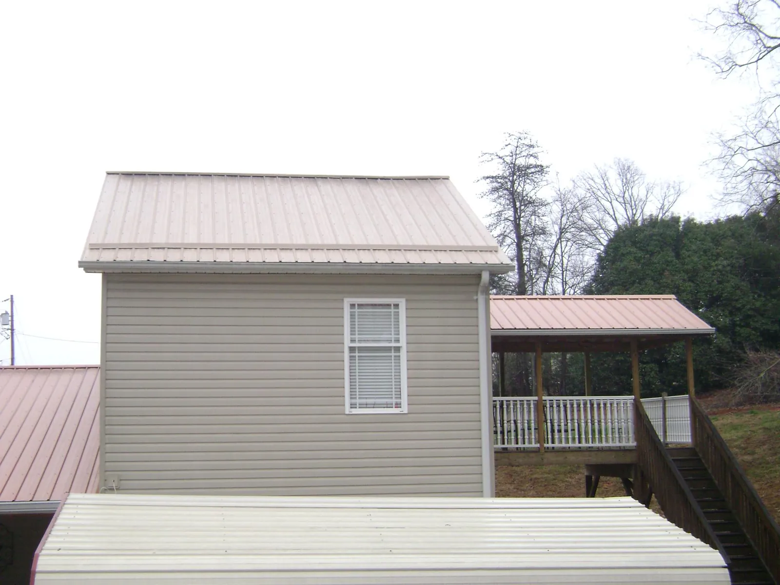 Tan metal roofs on a two story addition and attached porch, from a Roof Replacement job in Sherman Oaks