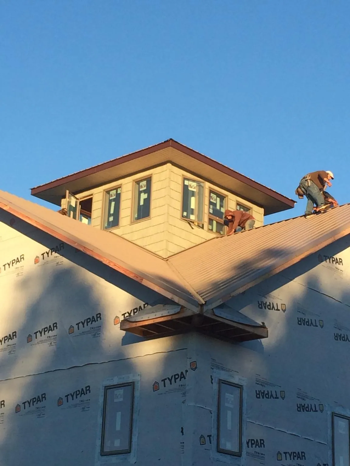 Roofers working around a rooftop cupola on a new metal roof at sunset — Roof Waterproofing in Sherman Oaks by Roofing Brothers
